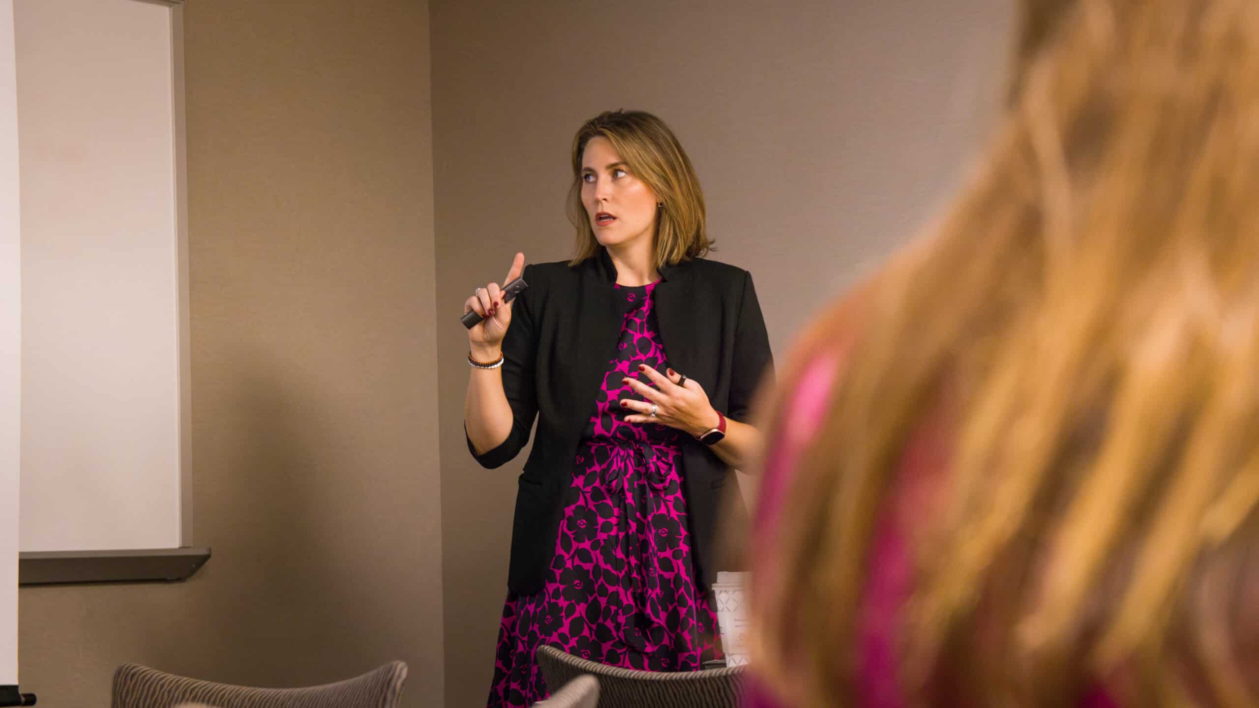 Photo of a presentation during the Copilot Brunch & Learn event. The presenter is standing in front of a screen displaying a slide, with attendees seated and listening attentively.