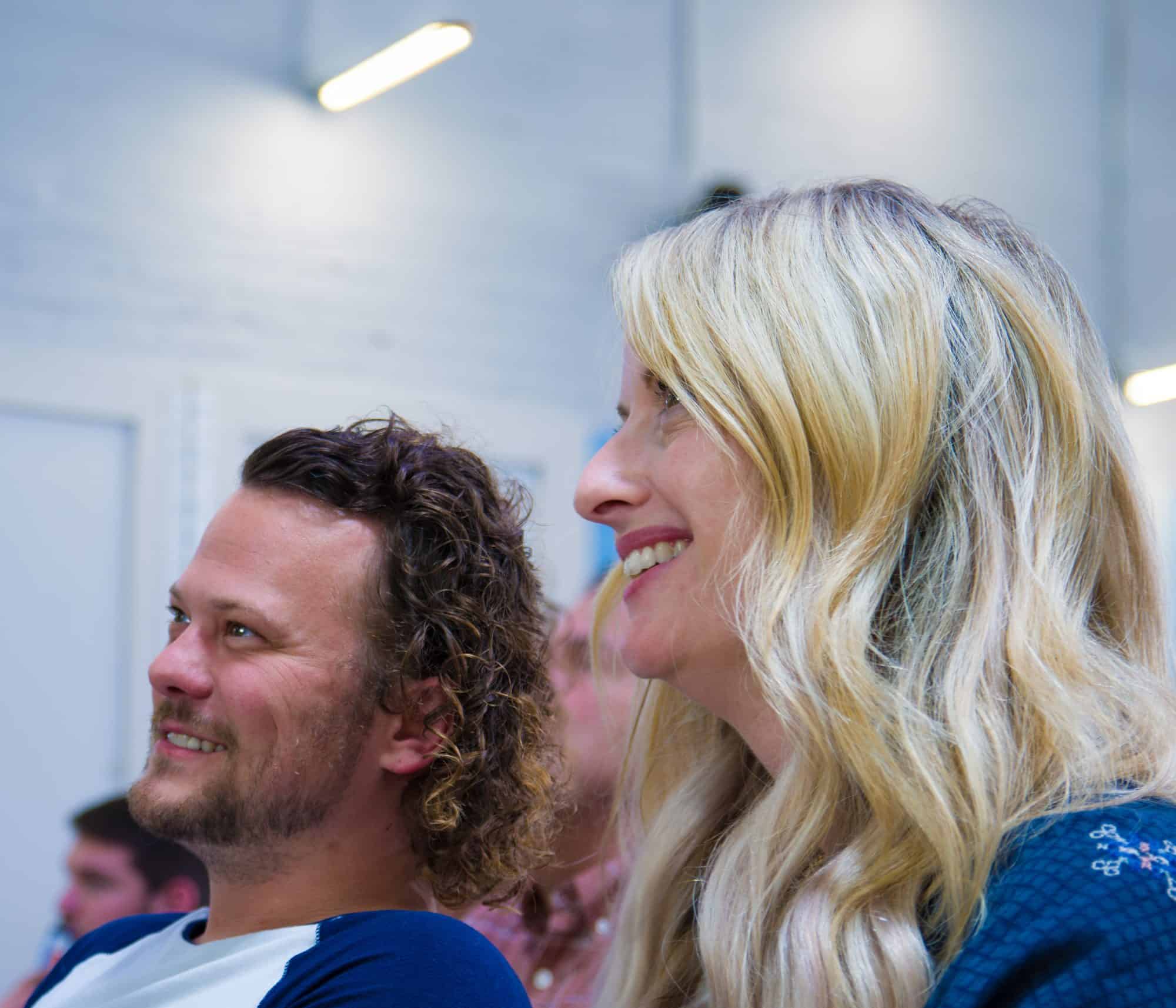 Two people smiling while listening to a company presentation